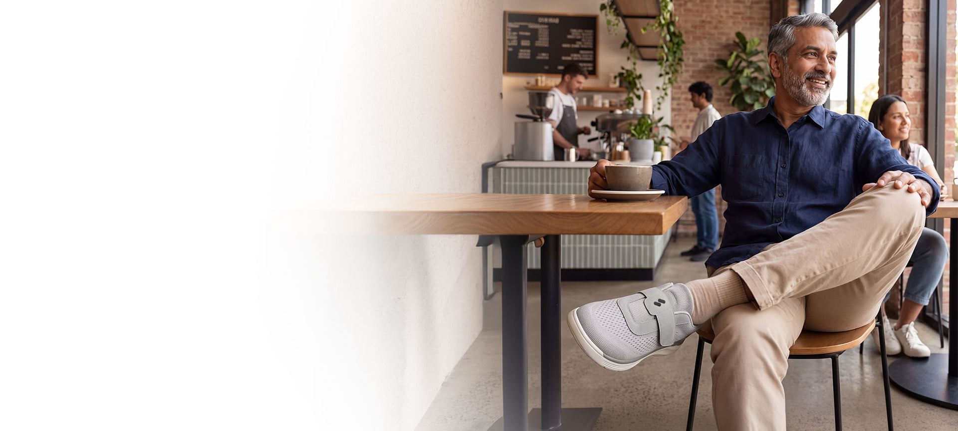 Man seated at a cafe table wearing a Silwer Ease slip-on shoe
