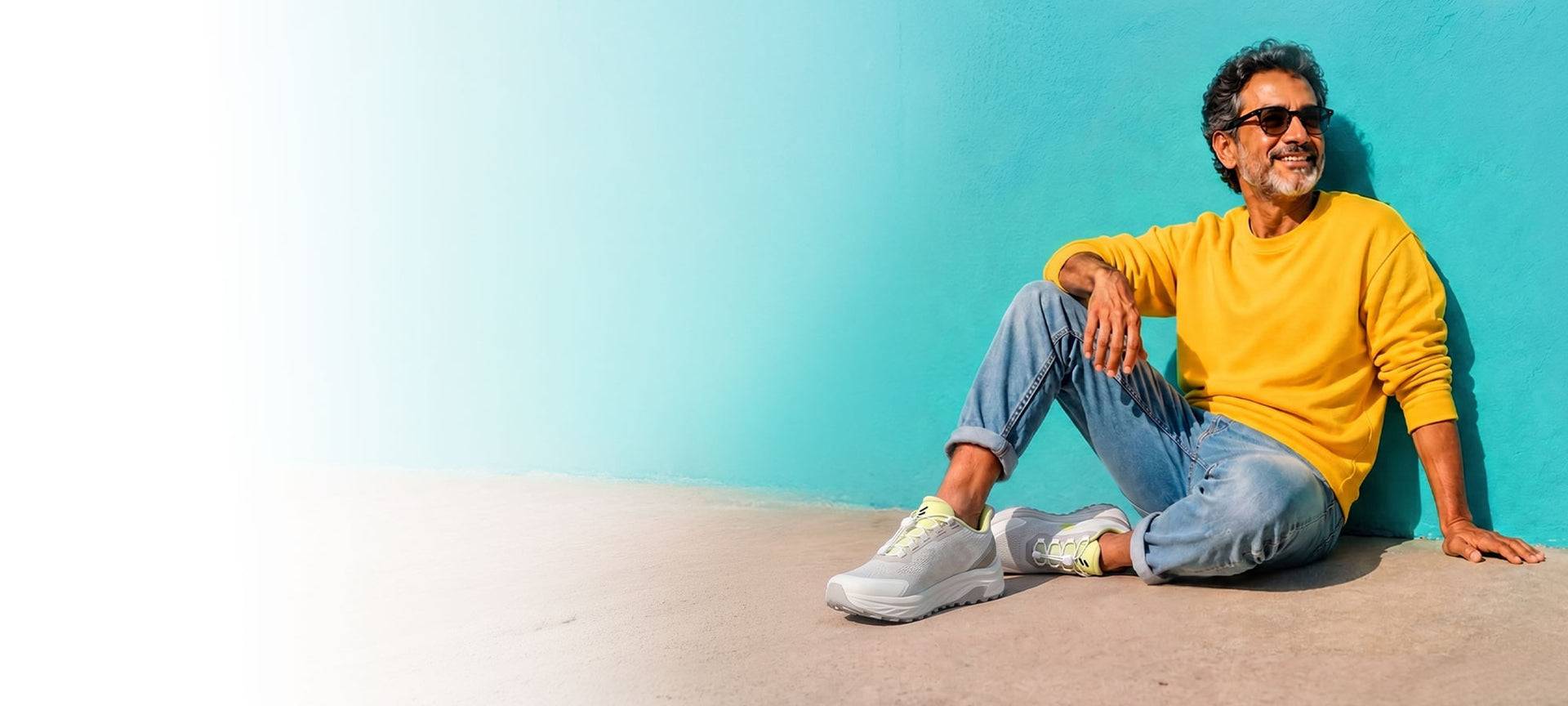 Man in his Fifties sitting against a teal wall wearing Silwer Active Lime White shoes